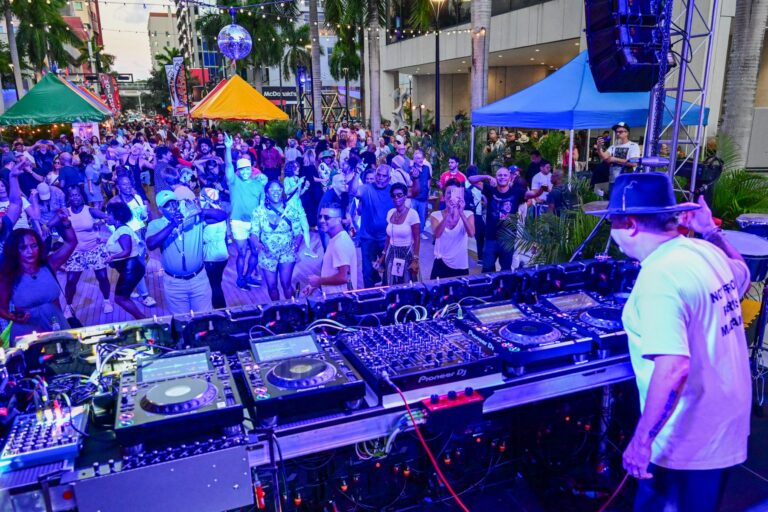 A DJ plays for a crowd dancing in the street at the Miami Book Fair Opening Day Block Party.